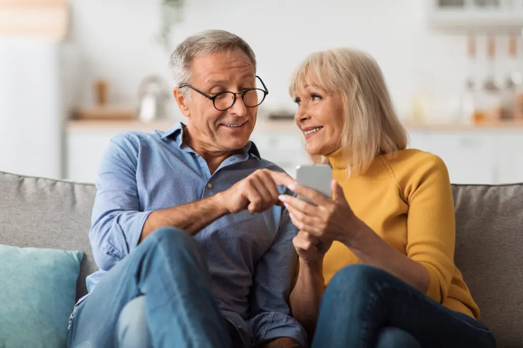 Xfinity Mobile customer in Kentucky enjoys fast WiFi on their device on the Premium Unlimited plan. IMAGE: Cheerful Senior Couple Texting Via Smartphone Sitting On Sofa At Home. Mature Spouses Using Application And Browsing Internet On Cellphone.