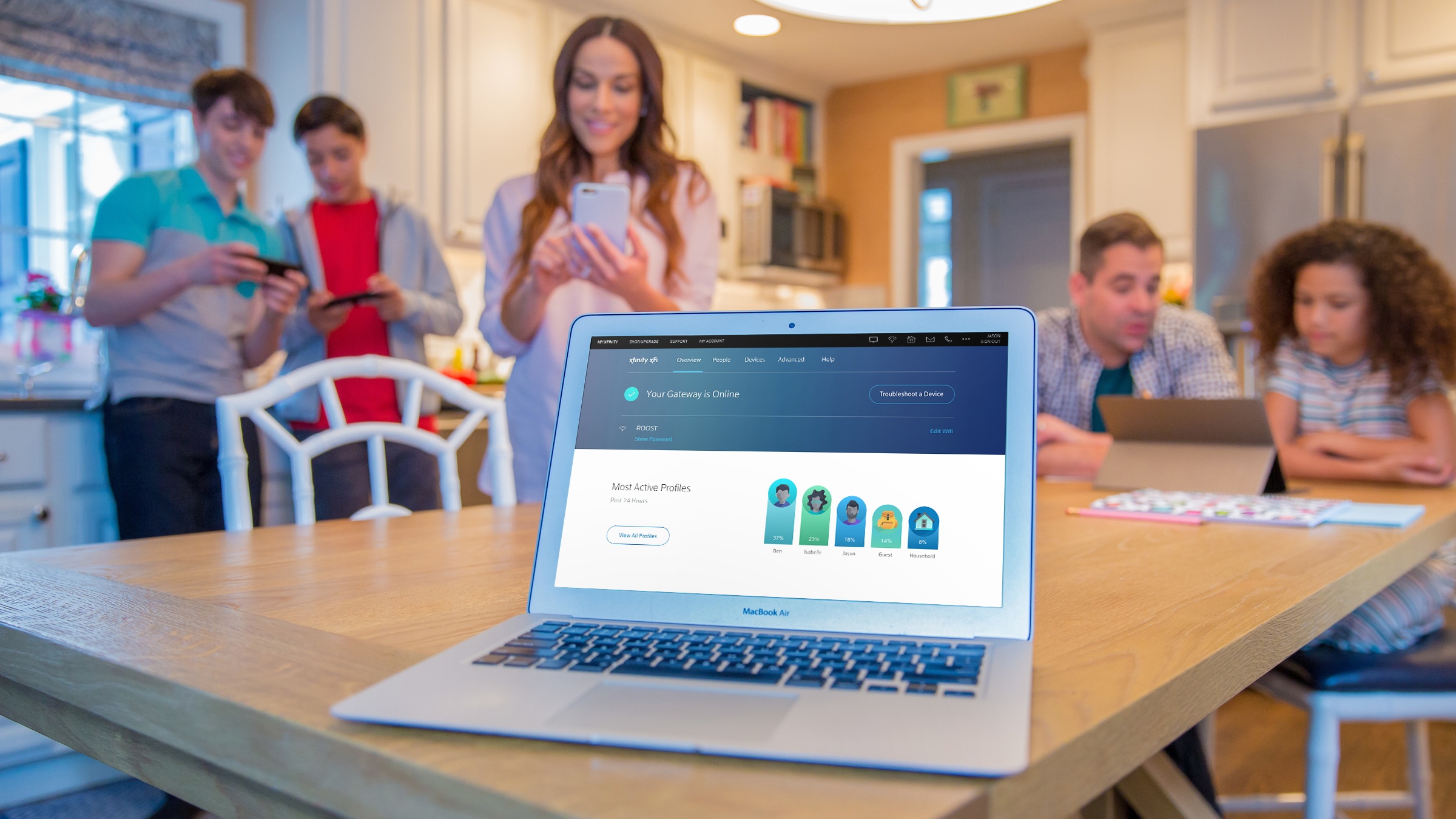 A family is gathered around a laptop displaying the Xfinity xFi control hub.