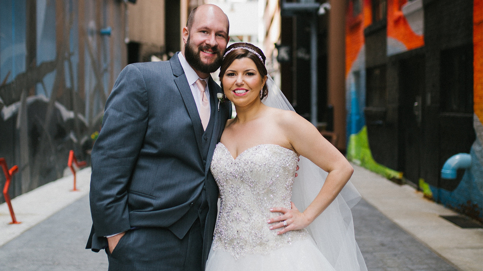 A bride and groom stand together in a street.